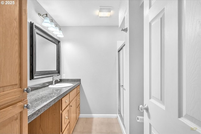 bathroom with an enclosed shower, vanity, baseboards, and tile patterned flooring