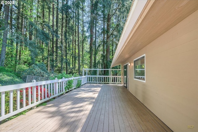 wooden terrace featuring a wooded view
