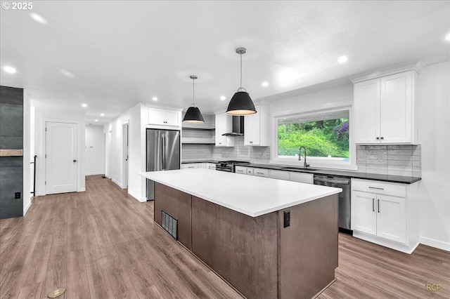 25125 SE Treehill Ln, Damascus, OR 97089 - kitchen with stainless steel appliances, wall chimney exhaust hood, wood finished floors, white cabinets, and decorative backsplash