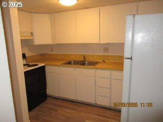 646/648 W Sixth Ave, Sutherlin, OR 97479 - kitchen with freestanding refrigerator, range with electric stovetop, a sink, ventilation hood, and wood finished floors