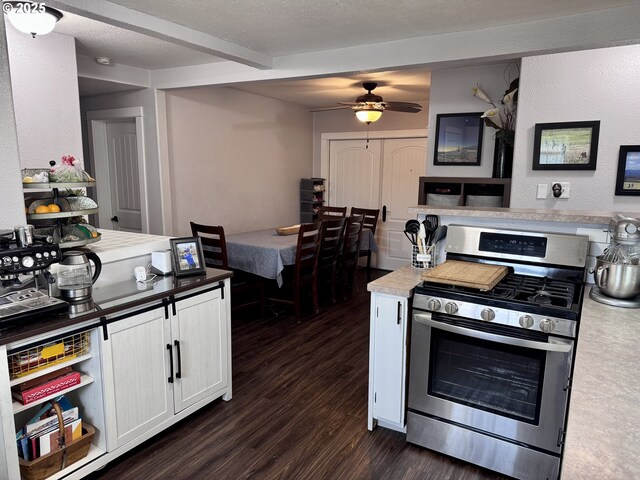 1918 Chestnut St, Baker City, OR 97814 - kitchen with gas range, dark wood-style floors, beamed ceiling, ceiling fan, and white cabinets