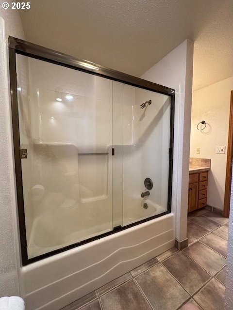 bathroom with vanity, bath / shower combo with glass door, tile patterned flooring, and a textured ceiling