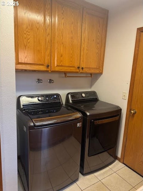 laundry area with light tile patterned flooring, cabinets, and washer and dryer