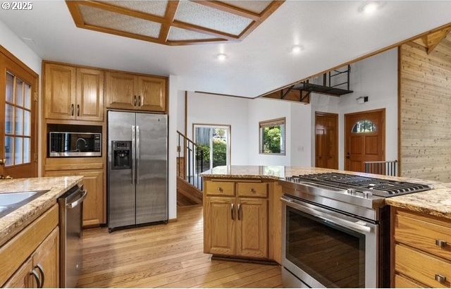 kitchen featuring light wood-type flooring, appliances with stainless steel finishes, and light stone countertops