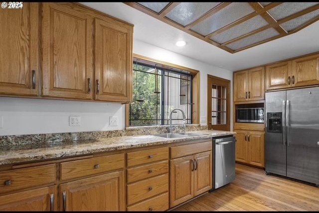 kitchen with light hardwood / wood-style flooring, sink, stainless steel appliances, and light stone countertops