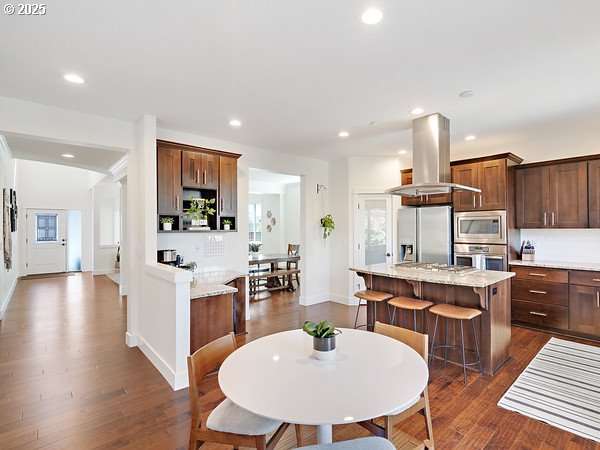 15582 SE Owl Ln, Happy Valley, OR 97015 - kitchen featuring island exhaust hood, appliances with stainless steel finishes, a center island, baseboards, and recessed lighting