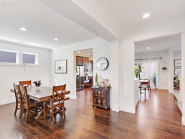 15582 SE Owl Ln, Happy Valley, OR 97015 - dining space featuring dark wood finished floors, crown molding, recessed lighting, baseboards, and decorative columns