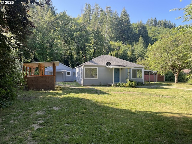154 Decoy Ln, Myrtle Creek, OR 97457 - rear view of house with a lawn, a shingled roof, a carport, and a wooded view