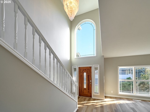 foyer entrance featuring light hardwood / wood-style flooring, a high ceiling, and a chandelier