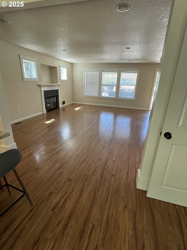 6721 N Yale St, Portland, OR 97203 - unfurnished living room featuring wood finished floors, plenty of natural light, a textured ceiling, and a glass covered fireplace