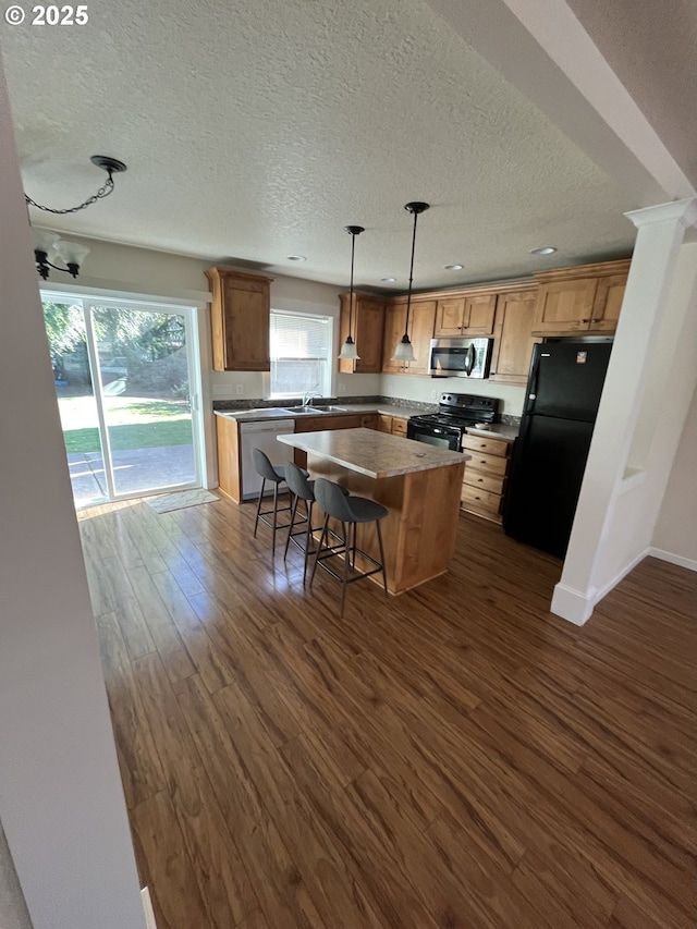 6721 N Yale St, Portland, OR 97203 - kitchen with black appliances, a textured ceiling, dark wood finished floors, a kitchen island, and recessed lighting