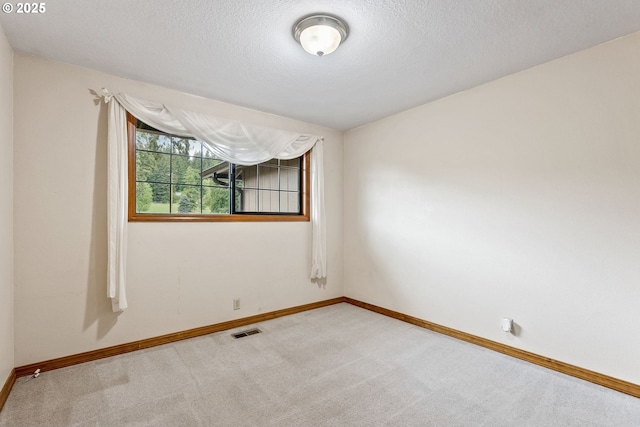 empty room with carpet, baseboards, and a textured ceiling
