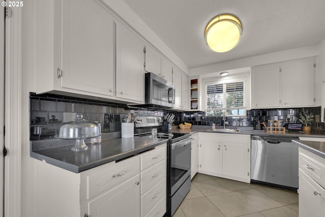 921 Williams St, Eugene, OR 97402 - kitchen with stainless steel appliances, a sink, tasteful backsplash, dark countertops, and white cabinetry