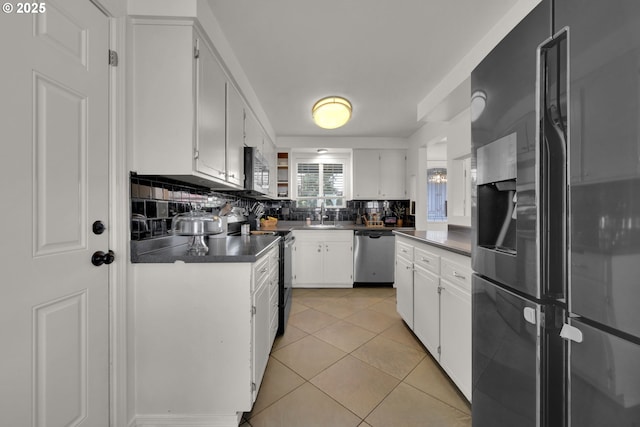921 Williams St, Eugene, OR 97402 - kitchen featuring appliances with stainless steel finishes, dark countertops, decorative backsplash, white cabinetry, and light tile patterned floors