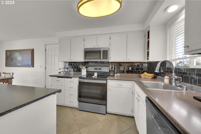 921 Williams St, Eugene, OR 97402 - kitchen featuring stainless steel appliances, a sink, tasteful backsplash, white cabinets, and light tile patterned floors