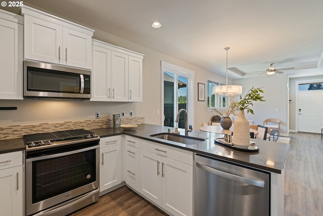 7314 NE 66th St, Vancouver, WA 98662 - kitchen featuring appliances with stainless steel finishes, a sink, dark countertops, a peninsula, and dark wood-type flooring