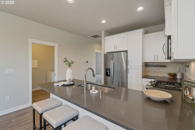 7314 NE 66th St, Vancouver, WA 98662 - kitchen featuring stainless steel appliances, a sink, white cabinets, dark wood finished floors, and a breakfast bar