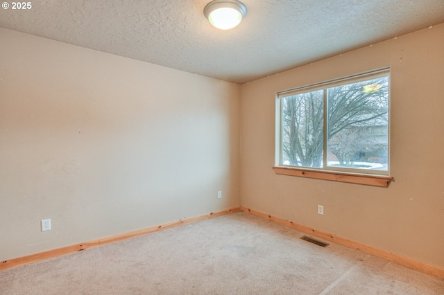 carpeted empty room with a textured ceiling