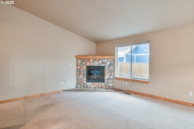 unfurnished living room featuring carpet flooring, a fireplace, vaulted ceiling, and a textured ceiling