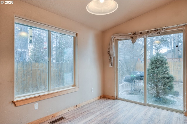 unfurnished room featuring hardwood / wood-style floors, vaulted ceiling, and plenty of natural light