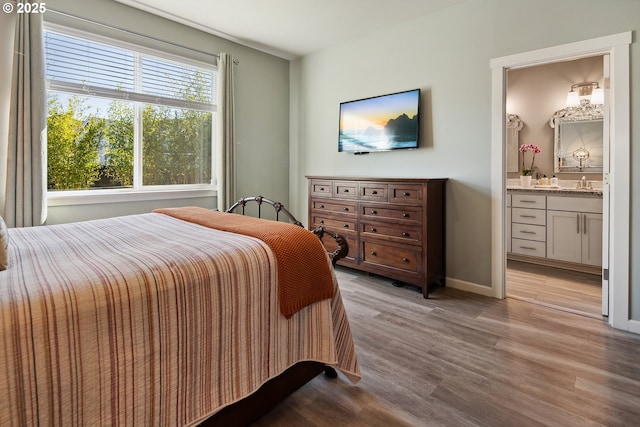 bedroom featuring ensuite bathroom, a sink, wet bar, light wood finished floors, and baseboards