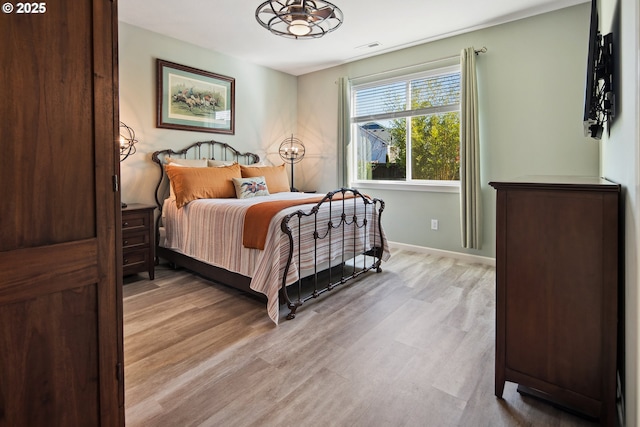 bedroom featuring visible vents, light wood-style flooring, and baseboards