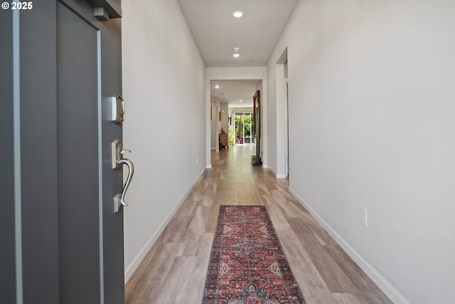 corridor featuring recessed lighting, light wood-style floors, and baseboards