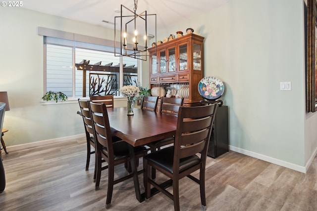 dining space with a notable chandelier, wood finished floors, and baseboards