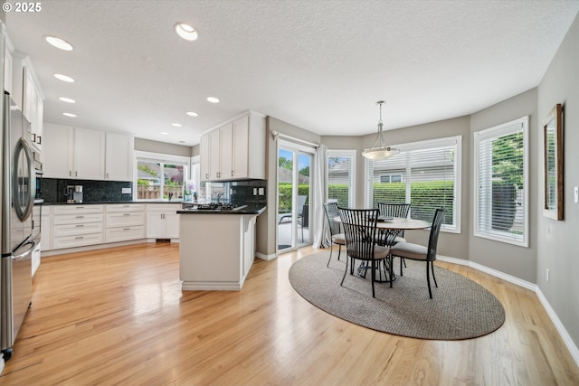 2678 SE Myrtlewood Way, Gresham, OR 97080 - kitchen featuring light wood-type flooring, white cabinets, backsplash, dark countertops, and freestanding refrigerator