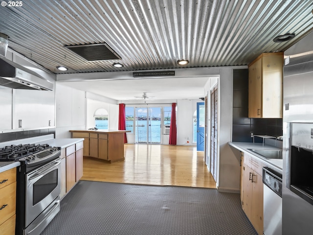 kitchen featuring light countertops, a ceiling fan, under cabinet range hood, and stainless steel appliances