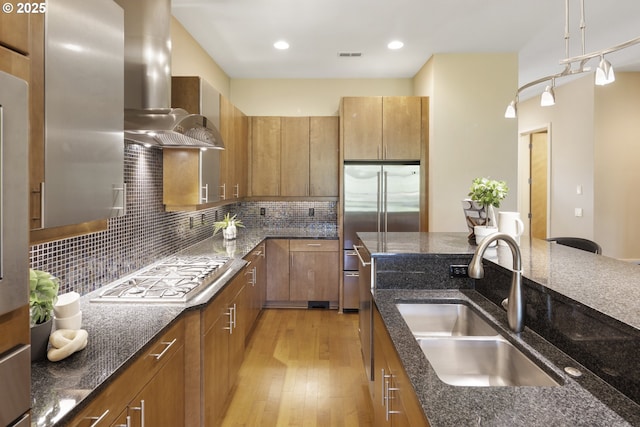 10122 SW Morrison St, Portland, OR 97225 - kitchen featuring wall chimney exhaust hood, stainless steel appliances, light wood-style floors, dark stone counters, and recessed lighting