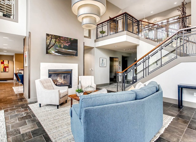 10122 SW Morrison St, Portland, OR 97225 - living room featuring a towering ceiling, a glass covered fireplace, stairway, stone tile flooring, and recessed lighting