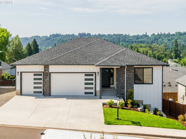 118 W 13th Way, La Center, WA 98629 - view of front of home featuring roof with shingles, an attached garage, driveway, board and batten siding, and a view of trees