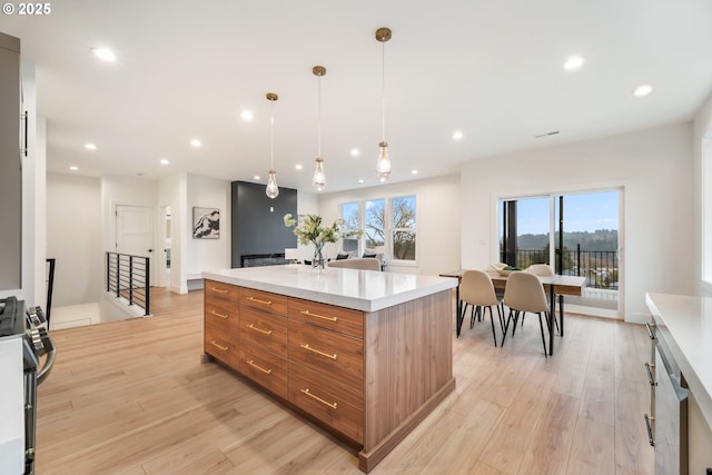 118 W 13th Way, La Center, WA 98629 - kitchen featuring stainless steel range with gas cooktop, brown cabinets, light wood finished floors, recessed lighting, and a center island