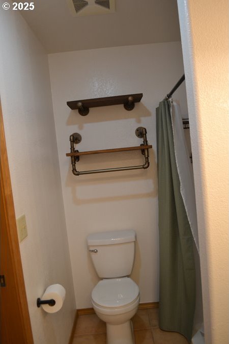 full bath featuring tile patterned flooring, toilet, a shower with shower curtain, baseboards, and visible vents