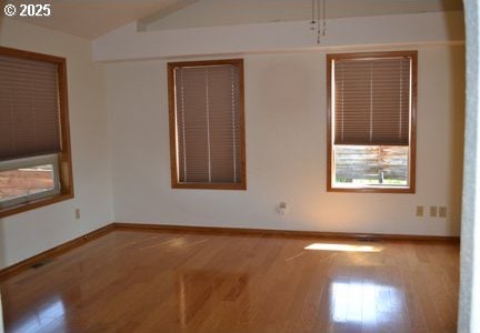 spare room with baseboards, wood finished floors, and vaulted ceiling