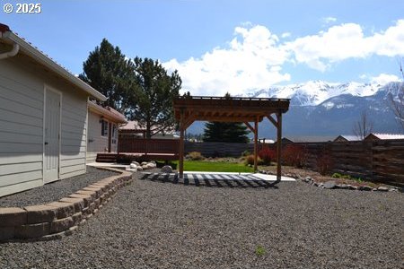 view of yard featuring a fenced backyard, a patio area, a mountain view, and a pergola