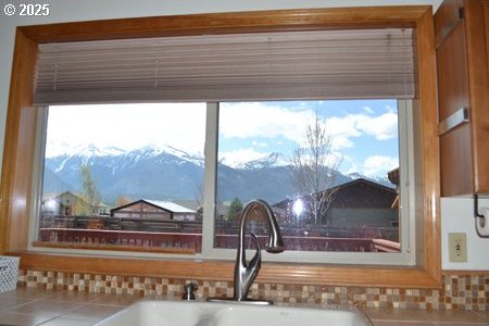 details featuring brown cabinetry, tasteful backsplash, a sink, light countertops, and a mountain view