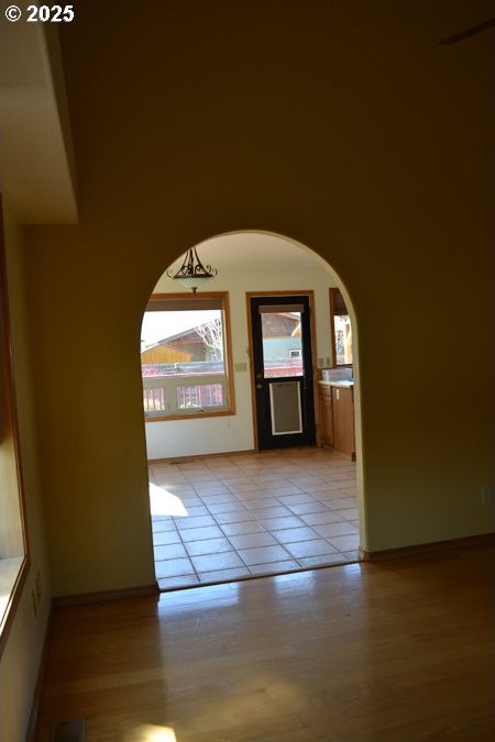 foyer entrance featuring light wood-style floors, arched walkways, and baseboards