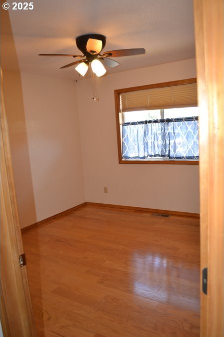 unfurnished room with ceiling fan, baseboards, and light wood-type flooring