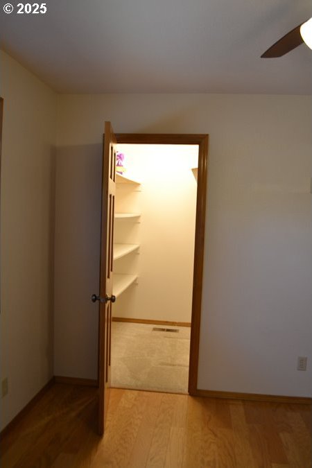spare room featuring a ceiling fan, baseboards, and light wood-type flooring