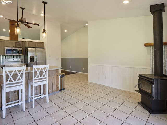 503 E Yacolt Rd, Yacolt, WA 98675 - kitchen featuring a wood stove, appliances with stainless steel finishes, wainscoting, ceiling fan, and light countertops