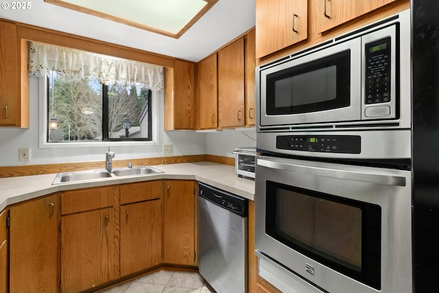 kitchen featuring stainless steel appliances, light countertops, a sink, and light tile patterned flooring