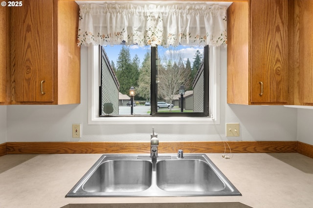 kitchen with brown cabinetry, light countertops, and a sink