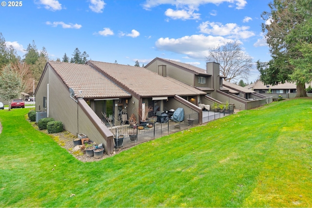 back of property with a tiled roof, a yard, a patio, and fence