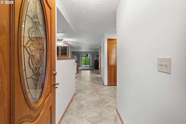 hall with baseboards and a textured ceiling