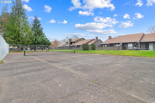 uncovered parking lot with a tennis court, fence, and a residential view