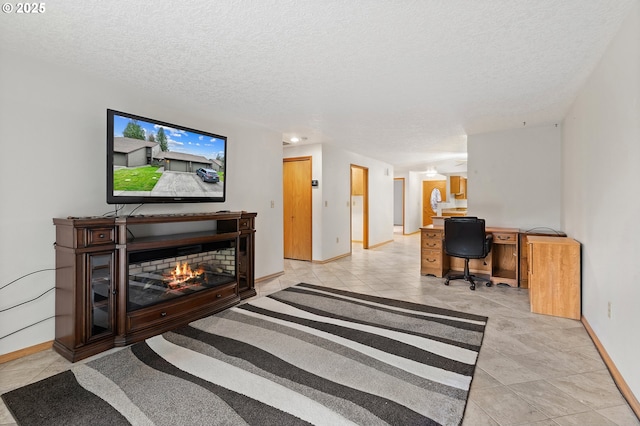 office area featuring a warm lit fireplace, baseboards, a textured ceiling, and light tile patterned flooring