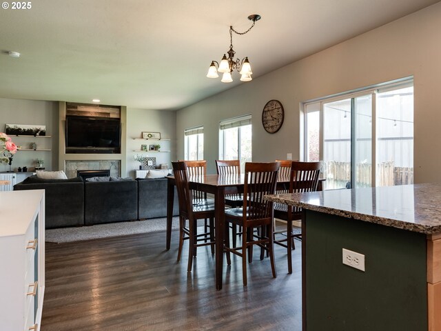 dining space with a chandelier, dark wood-style flooring, and a fireplace