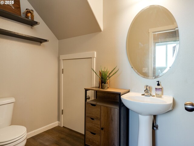 bathroom with toilet, wood finished floors, vaulted ceiling, and baseboards